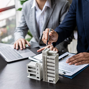 Businessman holding model small building house with property insurance at table in home sales office