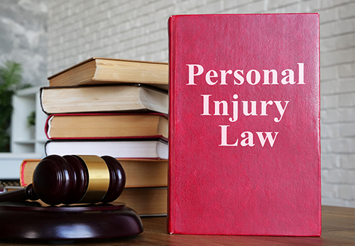 A red book titled "Personal Injury Law" next to a gavel and a stack of other law books.