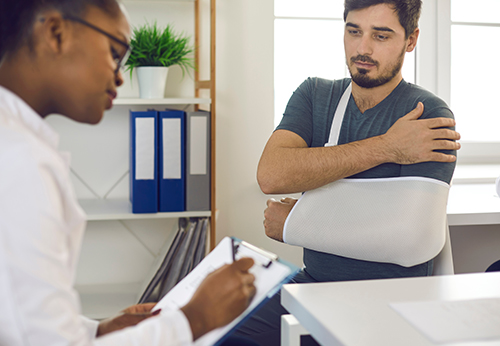 Lawyer discussing personal injury case with client in sling, Placer County mediation.