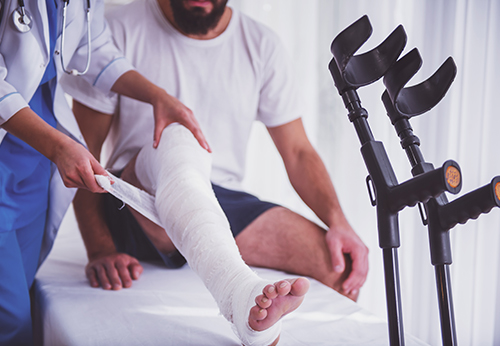 Doctor treating injured man’s leg during personal injury mediation evaluation